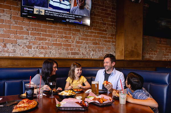 A family laughing together over pizza in a Barro's booth