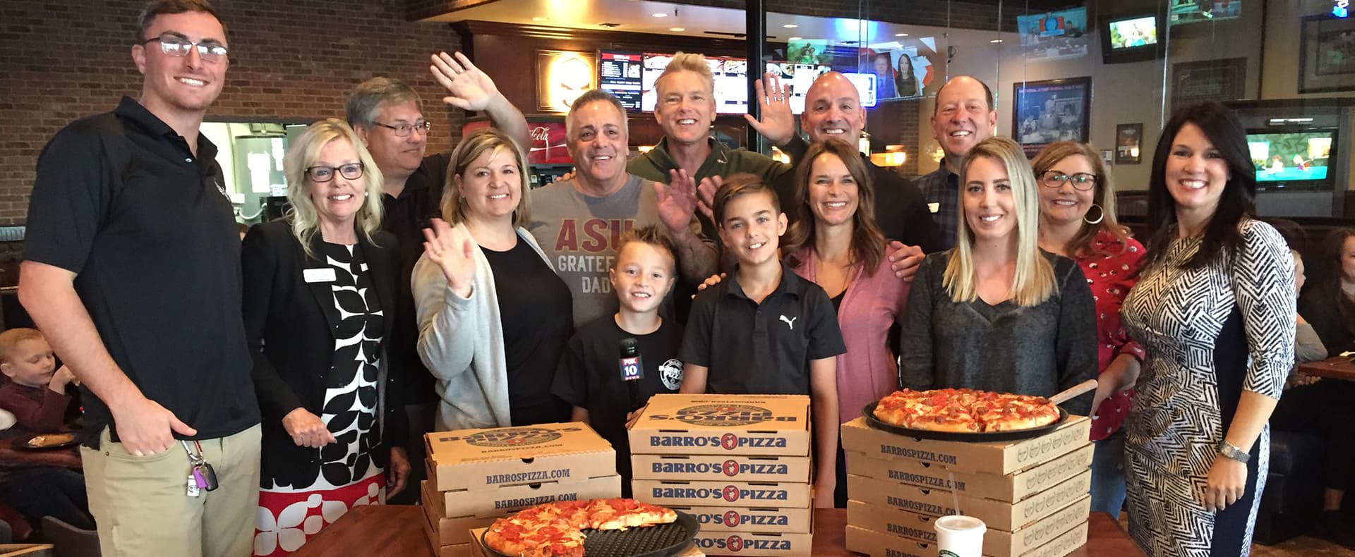 Barro's family and team holding pizza boxes at a community event